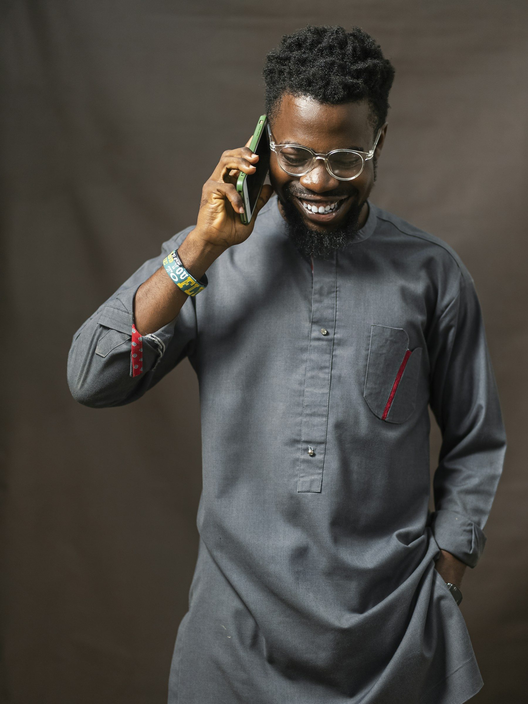 A smiling customer in a tailored kaftan on his phone